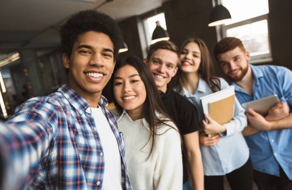 Young diverse group of students taking a selfie in a modern classroom, promoting youth education and community.