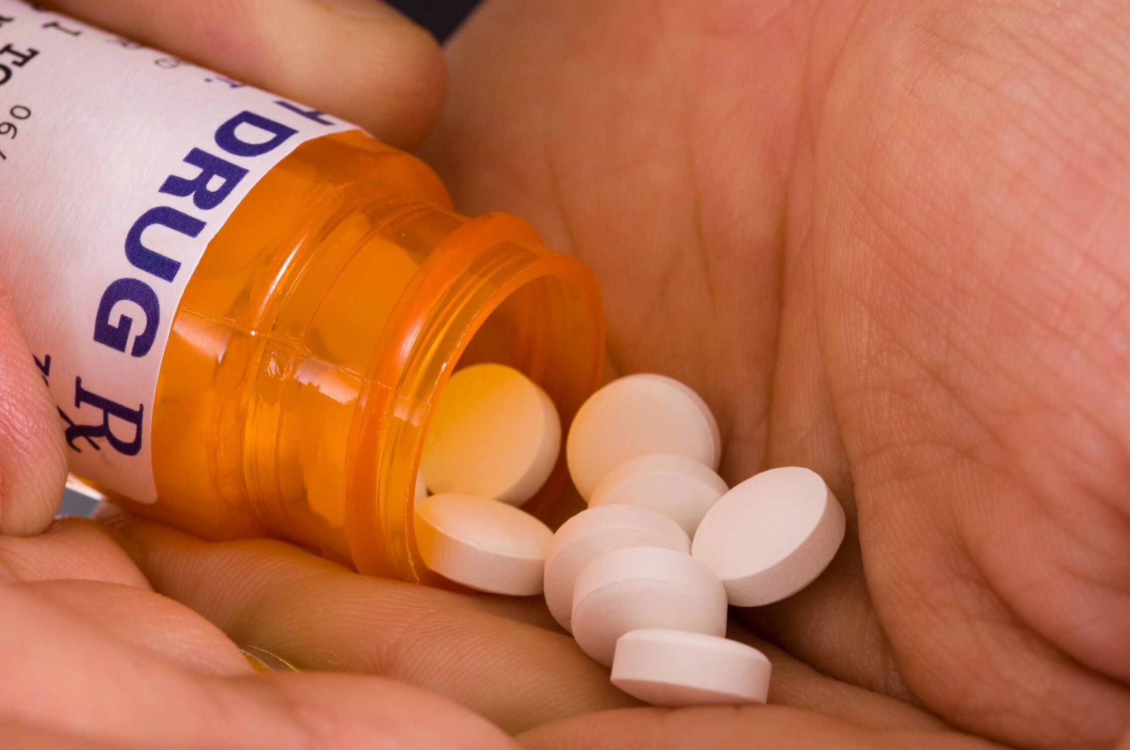 1. Prescription pill bottle with white tablets spilling out on hand.