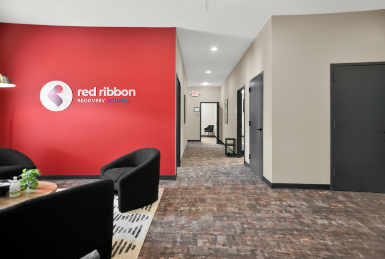 Comfortable recovery center lobby with Red Ribbon Recovery Indiana branding and inviting seating area.