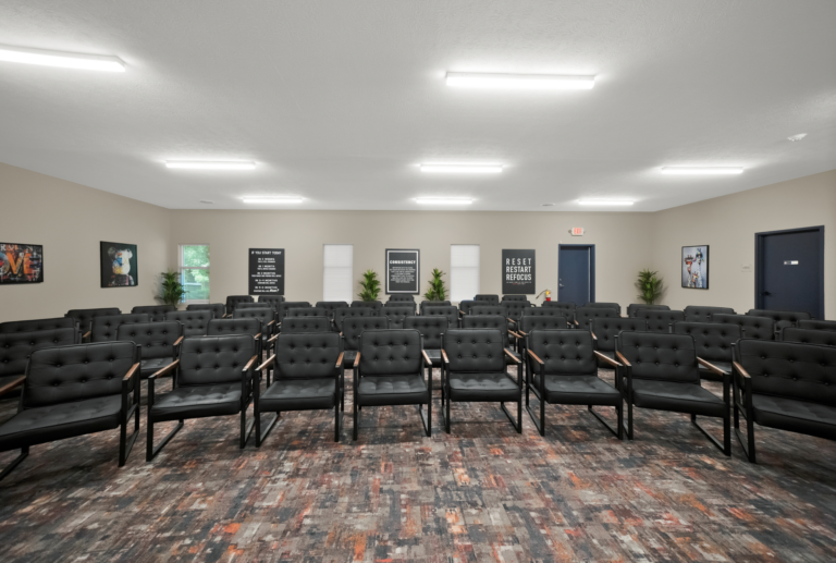 Comfortable recovery meeting room with black chairs and motivational posters, designed for addiction recovery support.