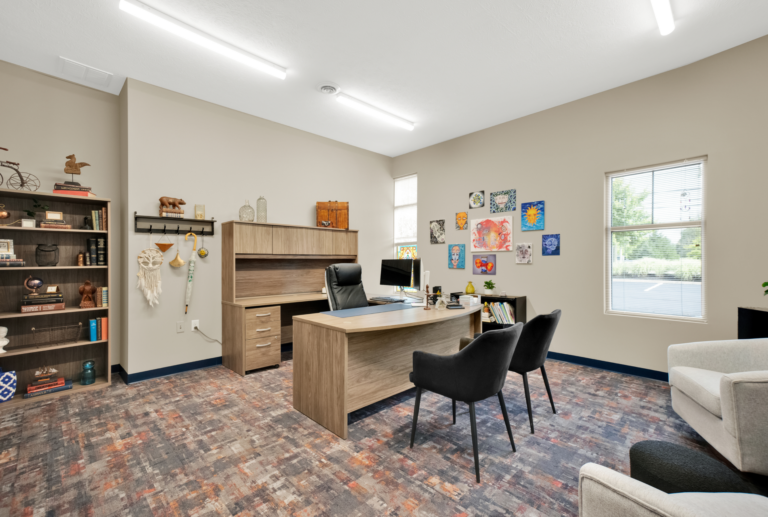 Warm welcoming therapy office with counseling desk, artwork, and seating for recovery sessions.