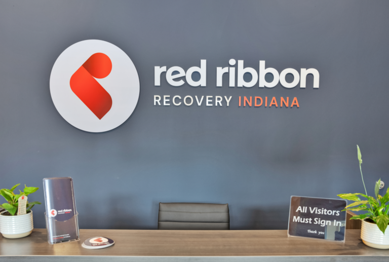 Red Ribbon Recovery Indiana office reception area with logo and welcome sign.