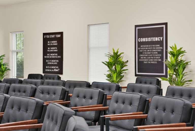 Comfortable black chairs in a recovery support group room with motivational posters and green plants.