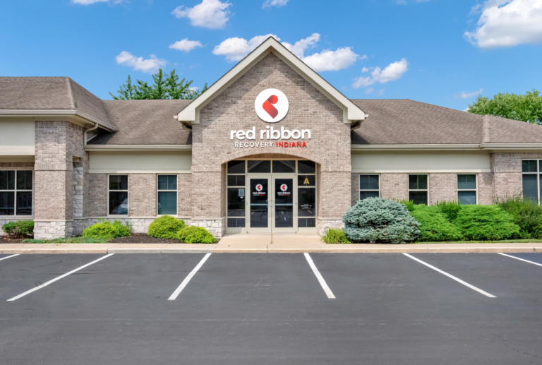 Bright exterior of Red Ribbon Recovery Indiana treatment center in Indiana, with welcoming entrance and parking lot.