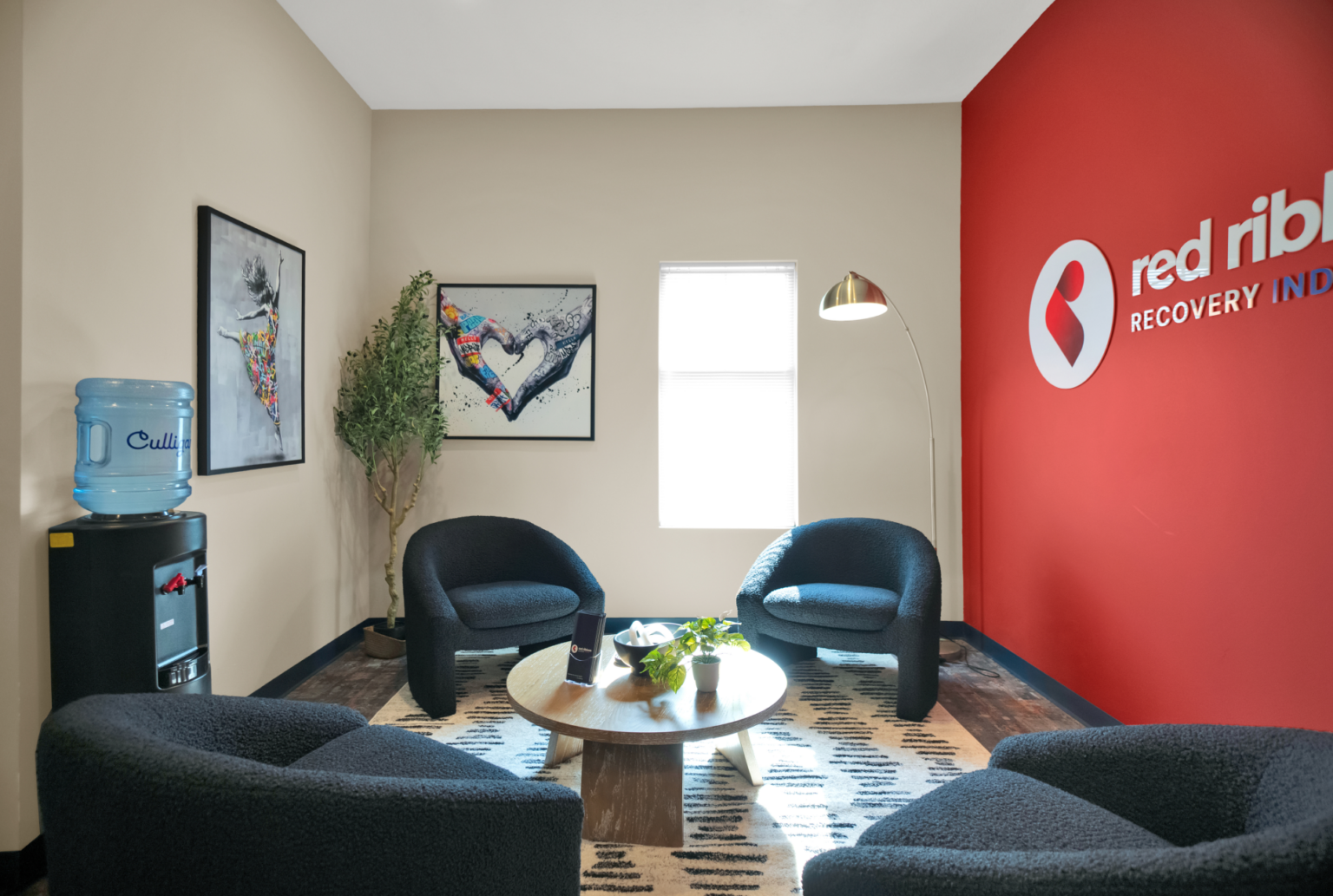 Supportive recovery center waiting room with Red Ribbon Recovery Indiana branding and comfortable seating.