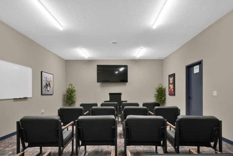 Comfortable addiction recovery support group room with chairs, whiteboard, and TV.