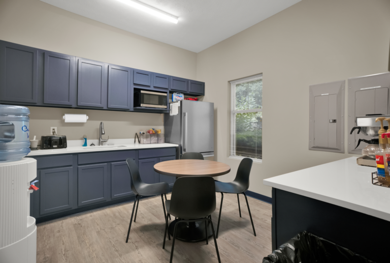 Clean recovery kitchen with blue cabinets and dining area at Red Ribbon Recovery Indiana.