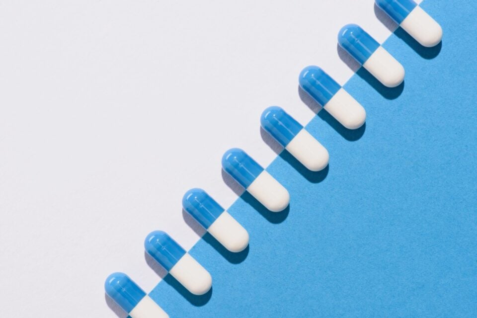 Blue and white capsules pills on blue and white background, medication, health, recovery, addiction support.