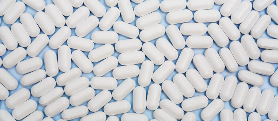 White pills on blue background, medication, capsules, pills, drug, pharmacy, medicine, health, recovery, addiction treatment.