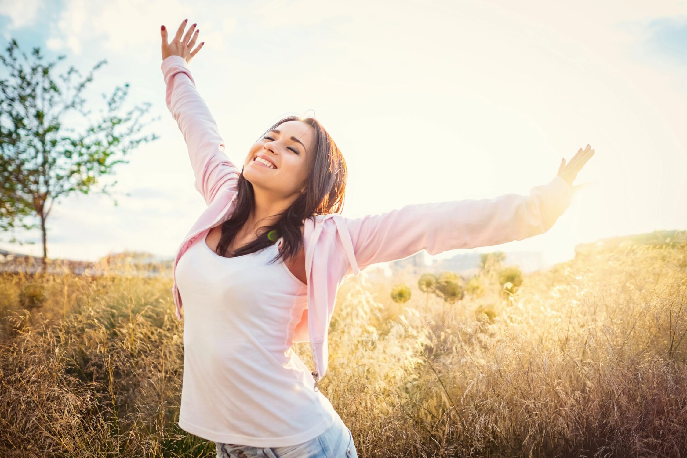Joyful woman embracing recovery and wellness outdoors on sunny day.