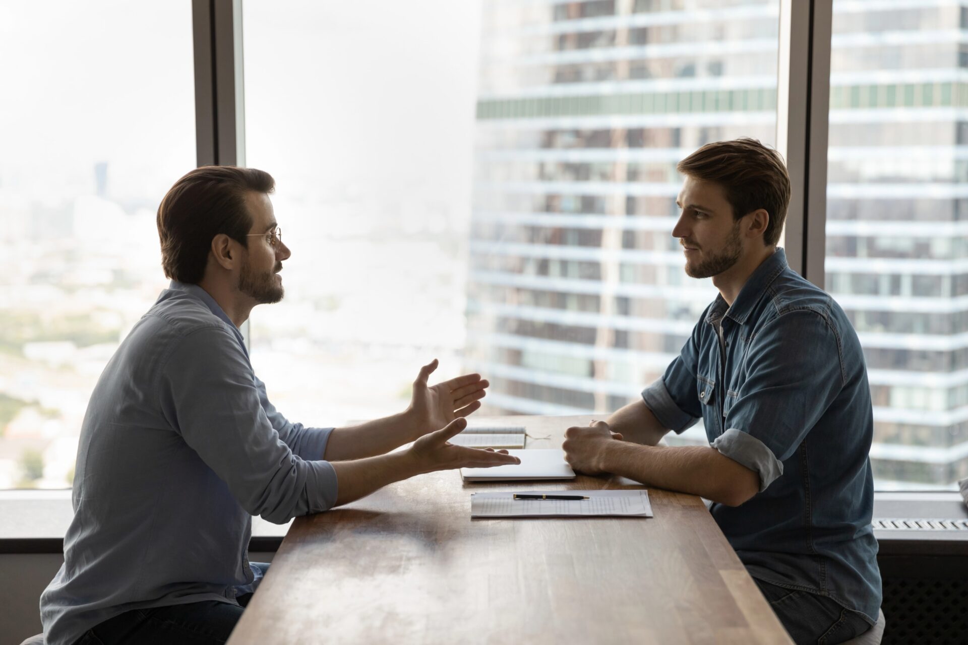 Conversational therapy for addiction recovery in an office setting with two men engaging in discussion.