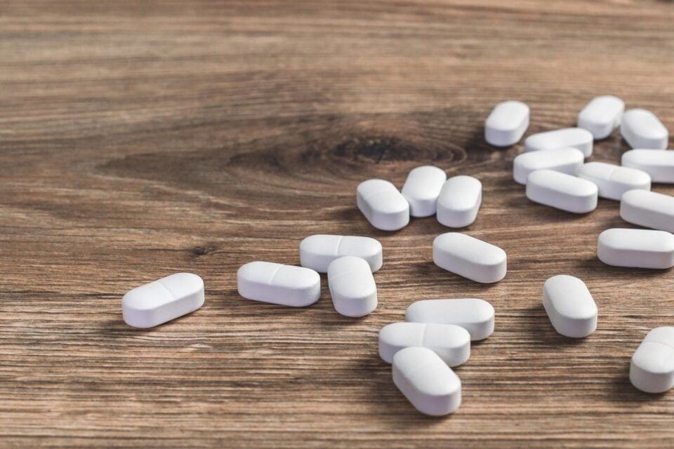Pills scattered on wooden surface, representing opioid medication and overdose risks.