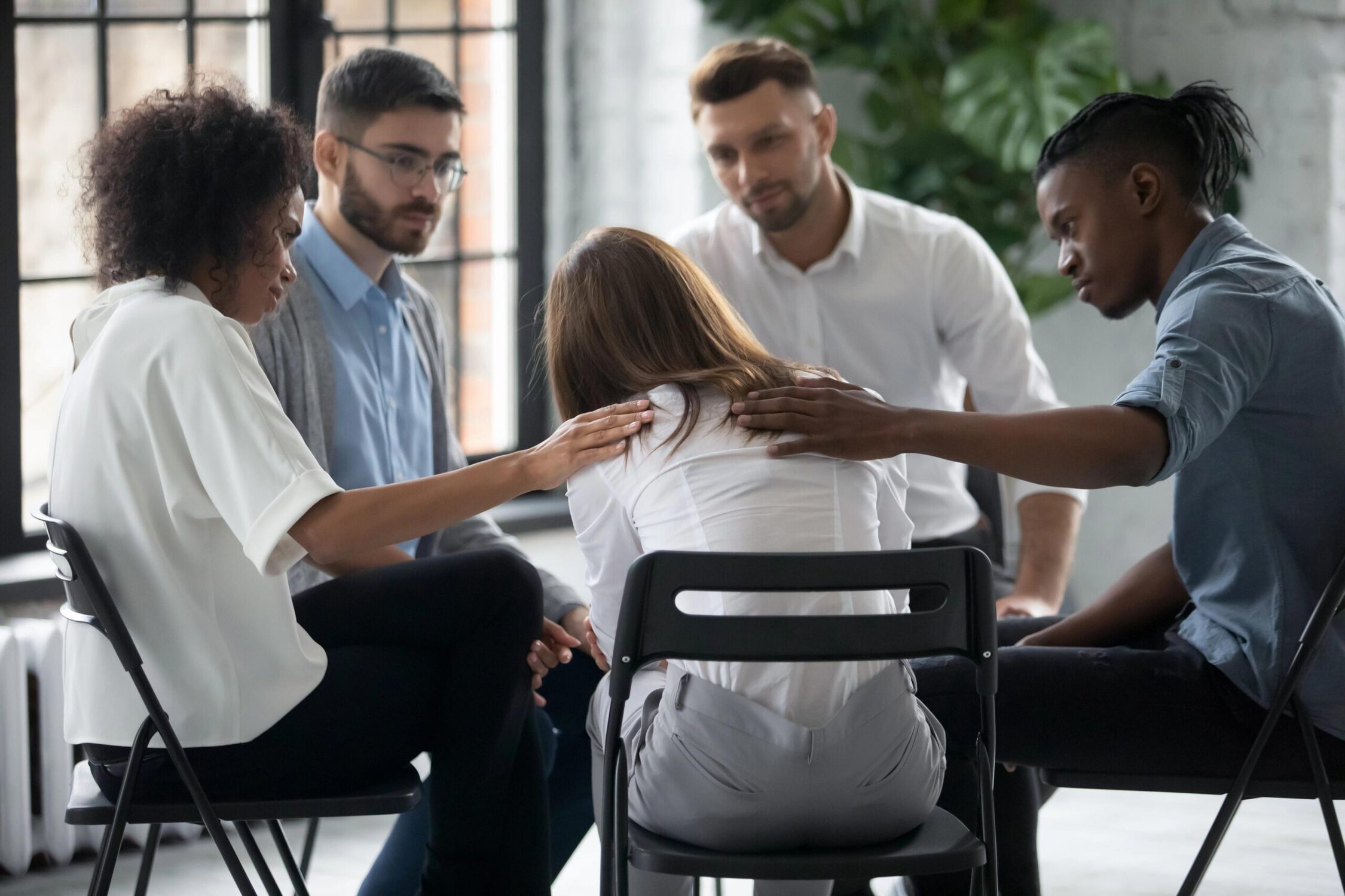 Helpless woman in a support group therapy session with diverse peers and counselor.