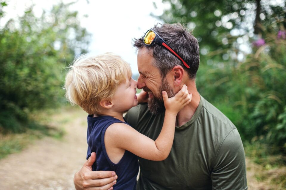 Father and young son sharing a tender moment outdoors.