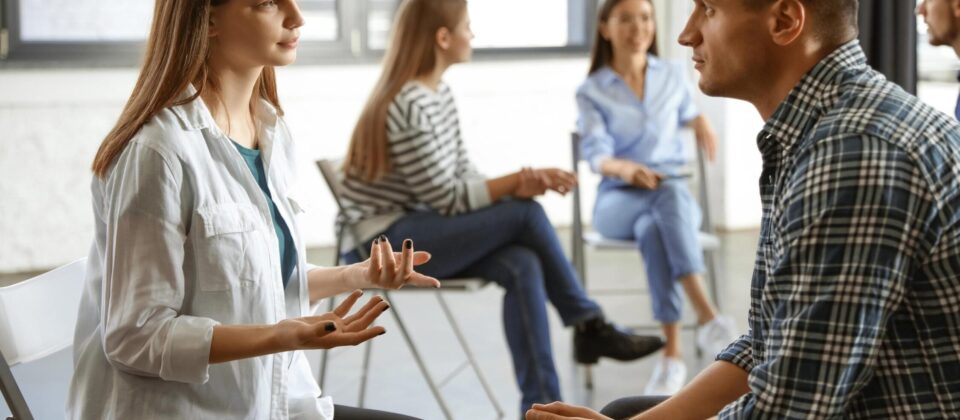 Group therapy session with individuals discussing recovery and support.
