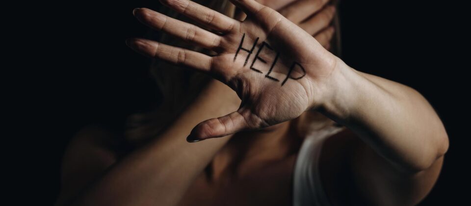 Help sign written on palm of woman with face partially covered, emphasizing mental health awareness.